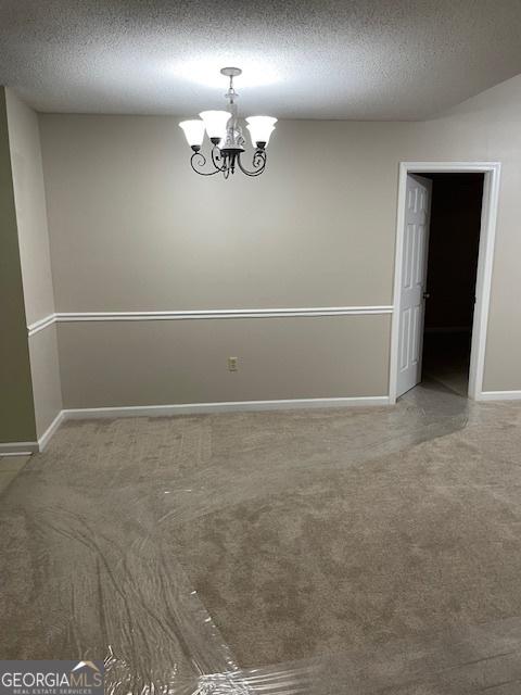 207 Oak Cir N, Stockbridge, GA 30281 - unfurnished room featuring carpet, a textured ceiling, and a chandelier