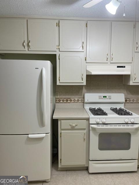 207 Oak Cir N, Stockbridge, GA 30281 - kitchen featuring white appliances, under cabinet range hood, light countertops, and light tile patterned floors