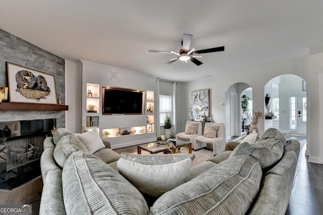 2410 Melton Common Dr, Dacula, GA 30019 - living room with arched walkways, ceiling fan, a stone fireplace, and wood finished floors