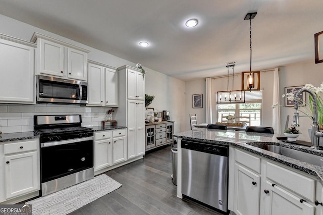 2410 Melton Common Dr, Dacula, GA 30019 - kitchen featuring stainless steel appliances, white cabinetry, backsplash, dark wood-style flooring, and dark stone countertops