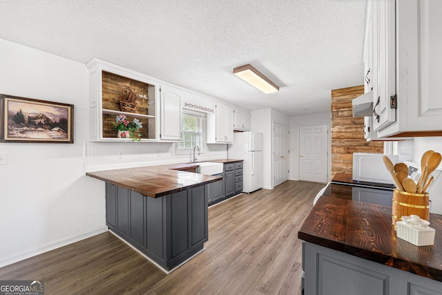 665 Center Of The World Rd, Canon, GA 30520 - kitchen with freestanding refrigerator, butcher block counters, a peninsula, wood finished floors, and range hood