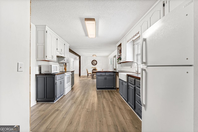 665 Center Of The World Rd, Canon, GA 30520 - kitchen featuring white appliances, white cabinets, light wood-type flooring, a textured ceiling, and gray cabinetry
