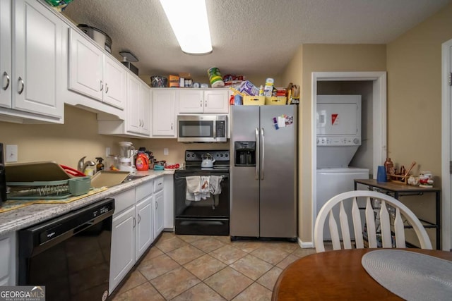2165 Milledge Ave Unit F4, Athens, GA 30605 - kitchen with black appliances, stacked washer / drying machine, white cabinetry, light countertops, and a textured ceiling