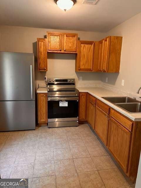 519 Roy St SW, Atlanta, GA 30310 - kitchen with appliances with stainless steel finishes, light countertops, brown cabinets, and light tile patterned floors