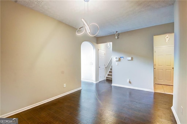 1643 Jackson Way, Atlanta, GA 30318 - unfurnished room with arched walkways, stairs, dark wood-style floors, a chandelier, and a textured ceiling