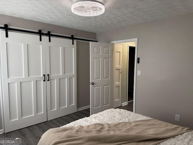 501 Carlton Rd Unit 3-D, Palmetto, GA 30268 - bedroom featuring a barn door, dark wood-type flooring, and a textured ceiling