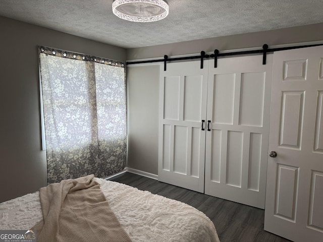 501 Carlton Rd Unit 3-D, Palmetto, GA 30268 - bedroom with a barn door, dark wood-type flooring, and a textured ceiling