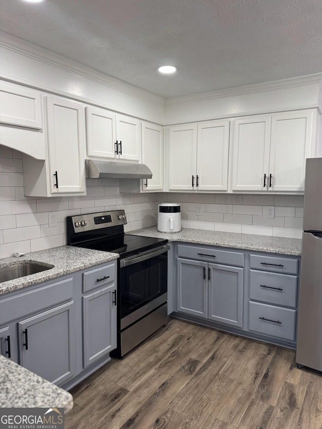501 Carlton Rd Unit 3-D, Palmetto, GA 30268 - kitchen with stainless steel appliances, under cabinet range hood, gray cabinets, ornamental molding, and dark wood-style flooring