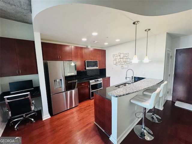 400 Peachtree St Unit 3412, Atlanta, GA 30308 - kitchen with appliances with stainless steel finishes, dark wood finished floors, a kitchen breakfast bar, pendant lighting, and decorative backsplash