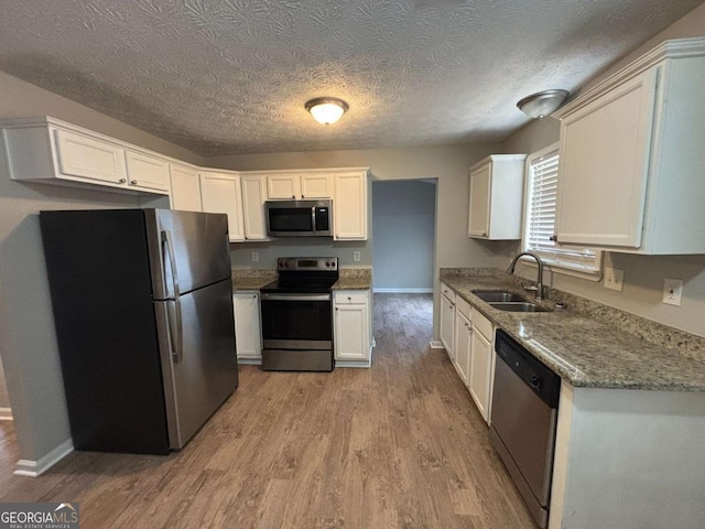 2183 Ramblewood Cir, Decatur, GA 30035 - kitchen featuring stainless steel appliances, light wood-type flooring, white cabinets, a textured ceiling, and light stone countertops