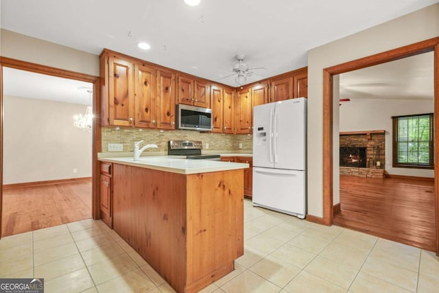 4211 Burnt Hickory Rd NW, Marietta, GA 30064 - kitchen featuring stainless steel appliances, light tile patterned floors, a peninsula, a stone fireplace, and light countertops