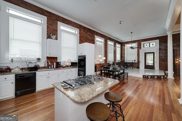 113 N Jefferson Ave, Eatonton, GA 31024 - kitchen featuring black appliances, light wood-style floors, light stone counters, ceiling fan, and a breakfast bar