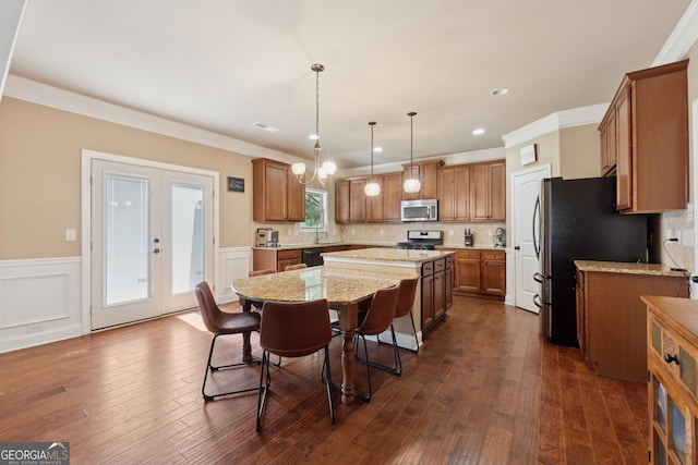 2629 Muskeg Ct SW, Atlanta, GA 30331 - kitchen featuring appliances with stainless steel finishes, a kitchen island, brown cabinets, a wainscoted wall, and tasteful backsplash