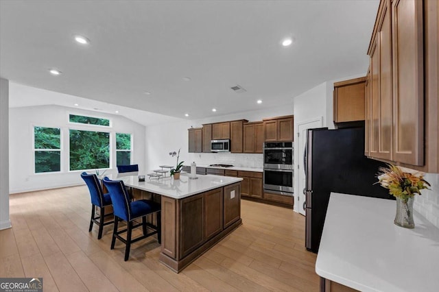 612 Michigan Cir, Hoschton, GA 30548 - kitchen with appliances with stainless steel finishes, tasteful backsplash, a kitchen island with sink, light countertops, and a kitchen bar