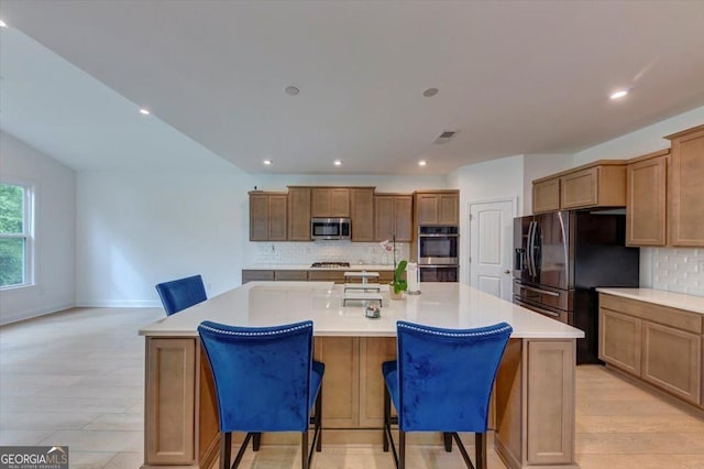 612 Michigan Cir, Hoschton, GA 30548 - kitchen featuring appliances with stainless steel finishes, backsplash, a large island, light countertops, and a breakfast bar