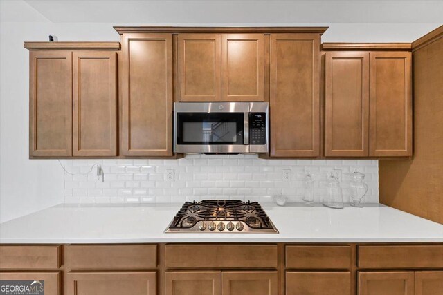 612 Michigan Cir, Hoschton, GA 30548 - kitchen featuring appliances with stainless steel finishes, light countertops, tasteful backsplash, and brown cabinets