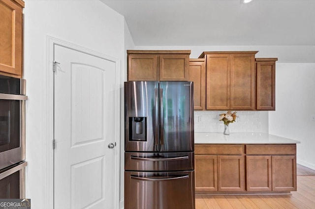 612 Michigan Cir, Hoschton, GA 30548 - kitchen featuring stainless steel refrigerator with ice dispenser, light countertops, light wood finished floors, tasteful backsplash, and brown cabinets