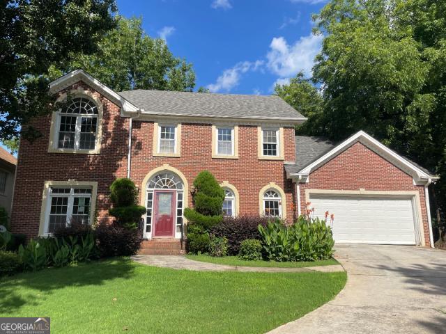 823 Mountain View Run, Stone Mountain, GA 30087 - colonial inspired home with a front lawn, an attached garage, brick siding, and concrete driveway