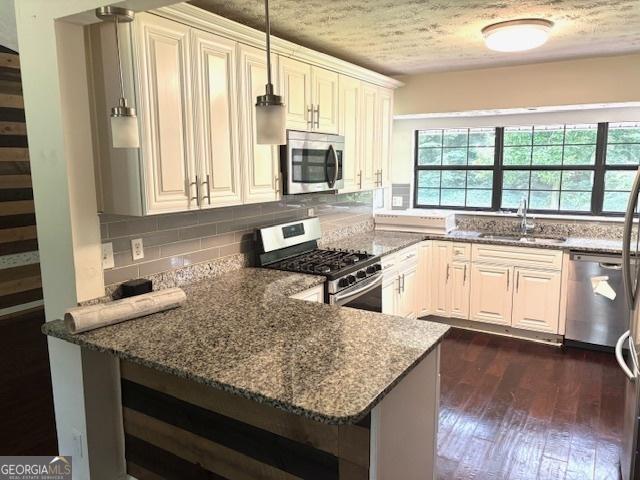 7813 Sugarland Dr, Jonesboro, GA 30236 - kitchen with appliances with stainless steel finishes, backsplash, dark stone counters, dark wood-style flooring, and decorative light fixtures
