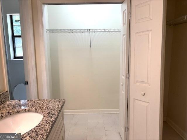7813 Sugarland Dr, Jonesboro, GA 30236 - bathroom featuring vanity, marble look tile flooring, and a spacious closet
