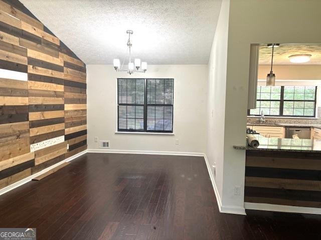 7813 Sugarland Dr, Jonesboro, GA 30236 - unfurnished dining area with wood walls, a chandelier, dark wood-type flooring, vaulted ceiling, and a textured ceiling