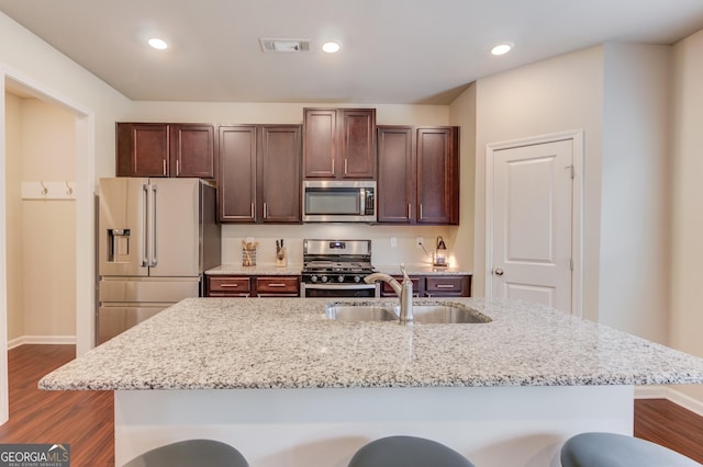 6841 Lancaster Xing, Flowery Branch, GA 30542 - kitchen with stainless steel appliances, dark wood-style flooring, a breakfast bar, dark brown cabinetry, and a kitchen island with sink