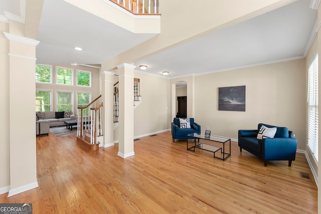 733 Miller Run, Atlanta, GA 30349 - living area with ornate columns, light wood-style floors, stairs, arched walkways, and crown molding