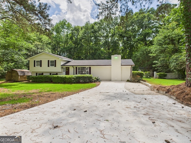 6417 Carey Pl, Macon, GA 31216 - split level home with a storage unit, concrete driveway, a front lawn, a chimney, and view of wooded area