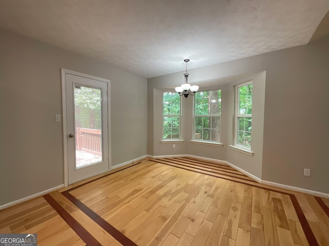 48 Glenhaven Ct, Douglasville, GA 30134 - unfurnished dining area featuring light wood-style floors, a chandelier, and a textured ceiling