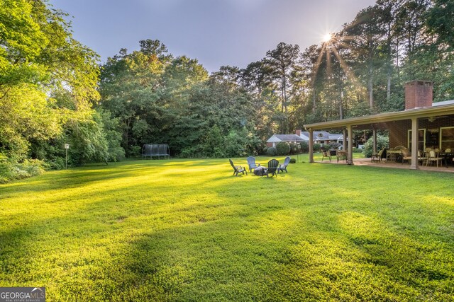 8815 Campbellton St, Douglasville, GA 30134 - view of grassy yard with a trampoline, a patio, and view of scattered trees