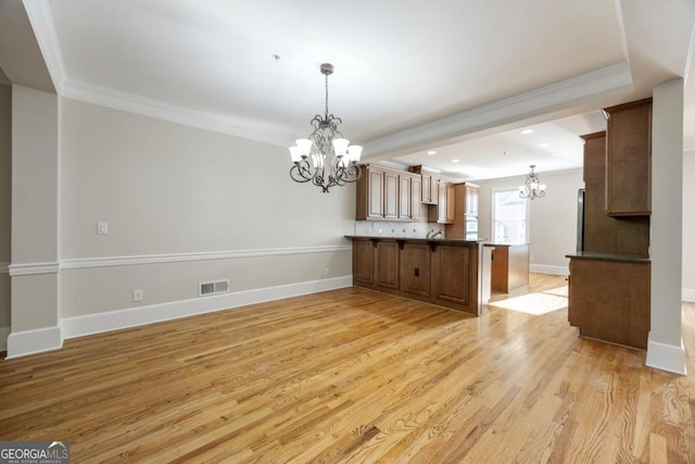 4742 Legacy Cove Ln, Smyrna, GA 30126 - kitchen with a chandelier, crown molding, a peninsula, light wood-style flooring, and hanging light fixtures