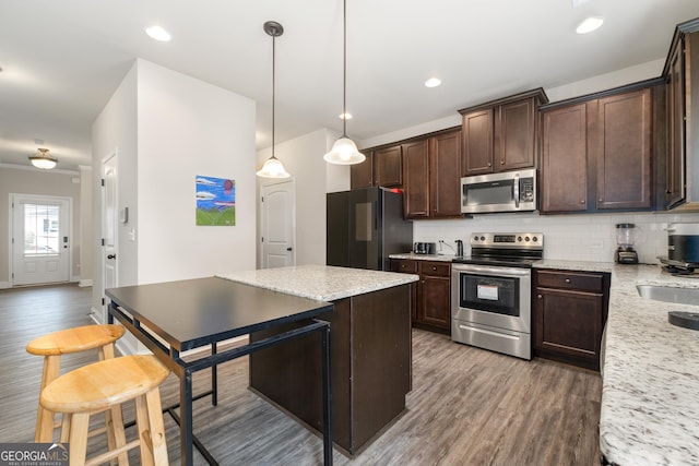2277 Church St, Hampton, GA 30228 - kitchen featuring stainless steel appliances, wood finished floors, dark brown cabinetry, tasteful backsplash, and pendant lighting
