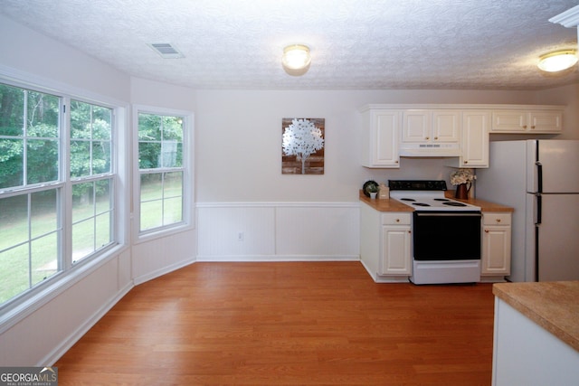 555 Flintlock Dr, Dacula, GA 30019 - kitchen featuring white appliances, under cabinet range hood, light wood-style flooring, white cabinets, and a wainscoted wall