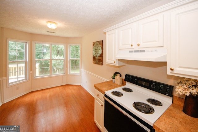 555 Flintlock Dr, Dacula, GA 30019 - kitchen featuring white electric range, under cabinet range hood, light wood finished floors, healthy amount of natural light, and a wainscoted wall