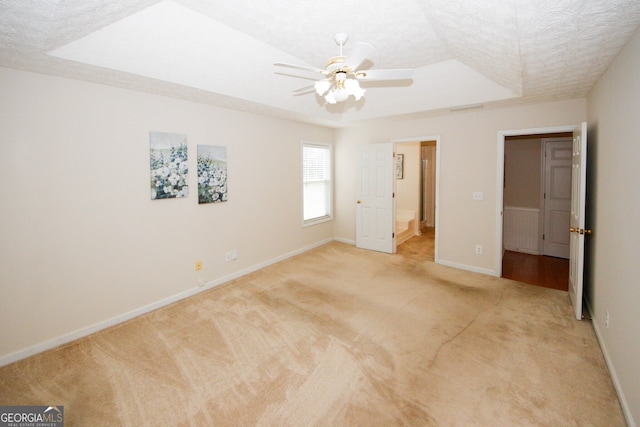 555 Flintlock Dr, Dacula, GA 30019 - unfurnished bedroom featuring a raised ceiling, light carpet, ceiling fan, and a textured ceiling