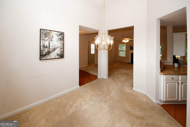 555 Flintlock Dr, Dacula, GA 30019 - unfurnished dining area featuring light carpet, a fireplace, a chandelier, and a towering ceiling