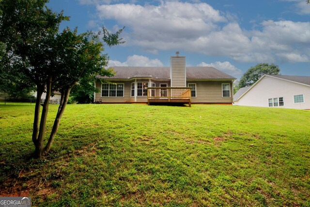 555 Flintlock Dr, Dacula, GA 30019 - back of property featuring a wooden deck, a lawn, and a chimney