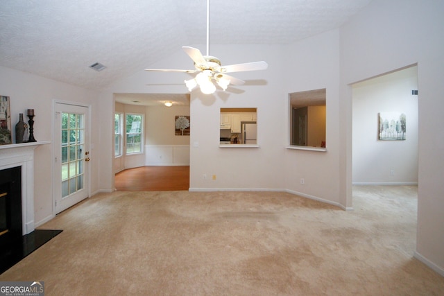 555 Flintlock Dr, Dacula, GA 30019 - unfurnished living room featuring light colored carpet, ceiling fan, vaulted ceiling, a glass covered fireplace, and a wainscoted wall
