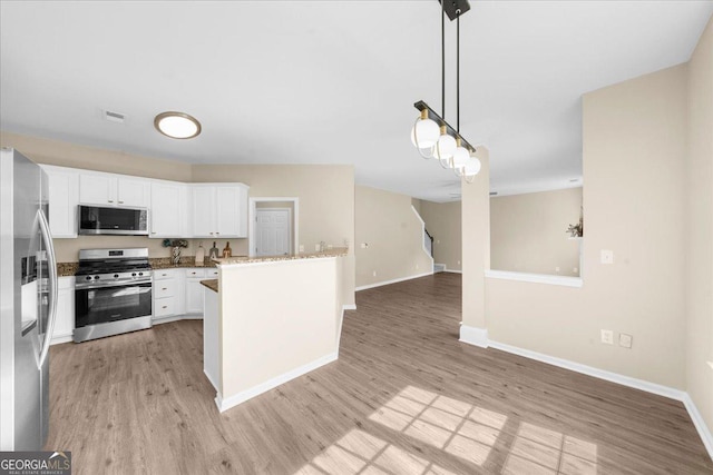 3559 Reservoir Pass, Acworth, GA 30101 - kitchen with appliances with stainless steel finishes, light wood finished floors, white cabinetry, hanging light fixtures, and open floor plan