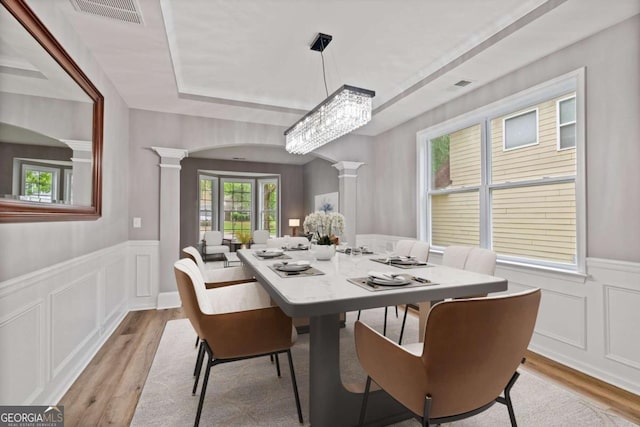 950 Mill Creek Ave, Canton, GA 30115 - dining room featuring ornate columns, light wood-type flooring, wainscoting, a decorative wall, and a raised ceiling