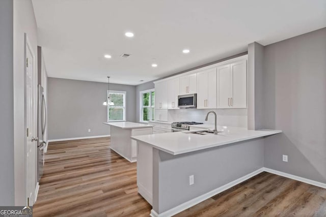 950 Mill Creek Ave, Canton, GA 30115 - kitchen featuring stainless steel appliances, a center island, light wood-style flooring, white cabinets, and light countertops