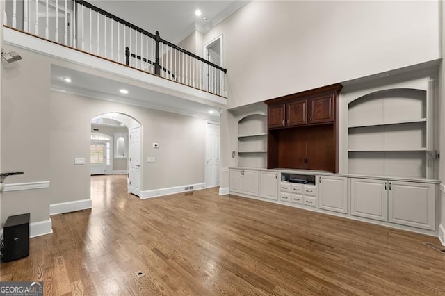 3311 Marina View Way, Gainesville, GA 30506 - unfurnished living room featuring a towering ceiling, crown molding, arched walkways, wood finished floors, and recessed lighting