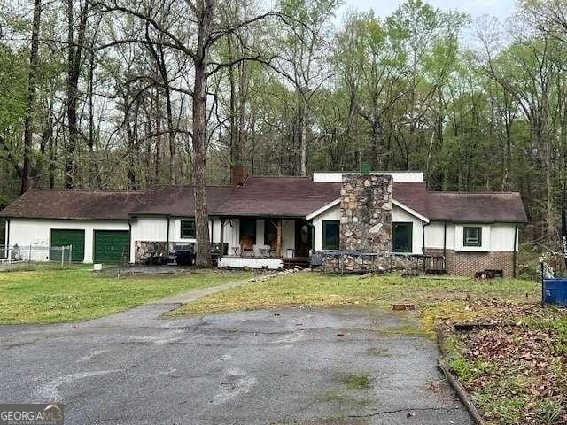 2497 Old Jackson Rd, Locust Grove, GA 30248 - view of front of property featuring a chimney, covered porch, a front yard, and a garage