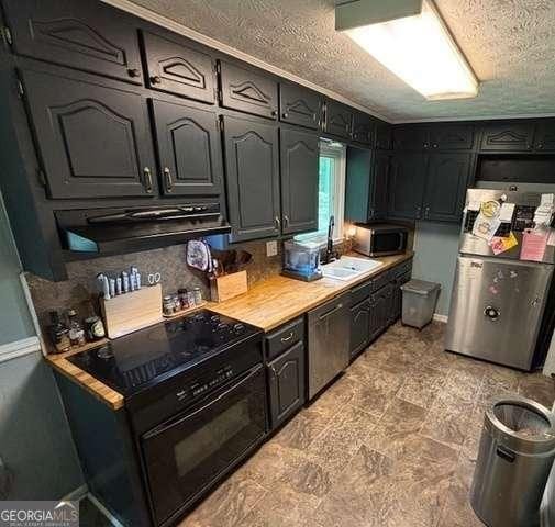 2497 Old Jackson Rd, Locust Grove, GA 30248 - kitchen featuring appliances with stainless steel finishes, range hood, light countertops, and a textured ceiling