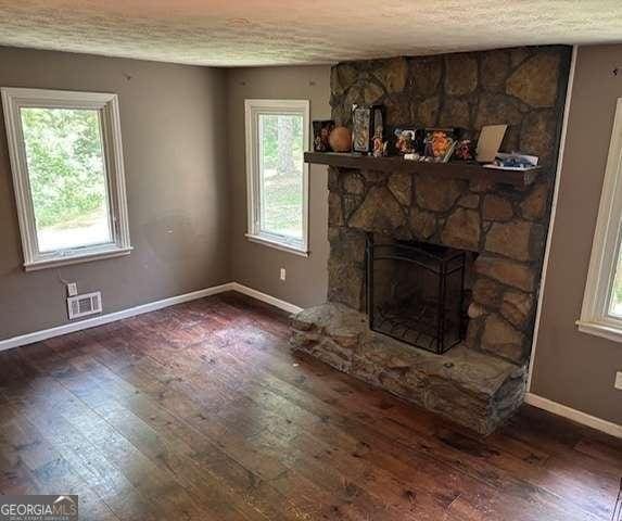 2497 Old Jackson Rd, Locust Grove, GA 30248 - unfurnished living room with wood-type flooring, a textured ceiling, and a fireplace