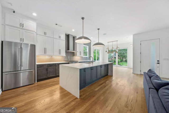 32 Walthall St NE Unit A, Atlanta, GA 30307 - kitchen featuring stainless steel appliances, wall chimney exhaust hood, open floor plan, light countertops, and light wood-type flooring