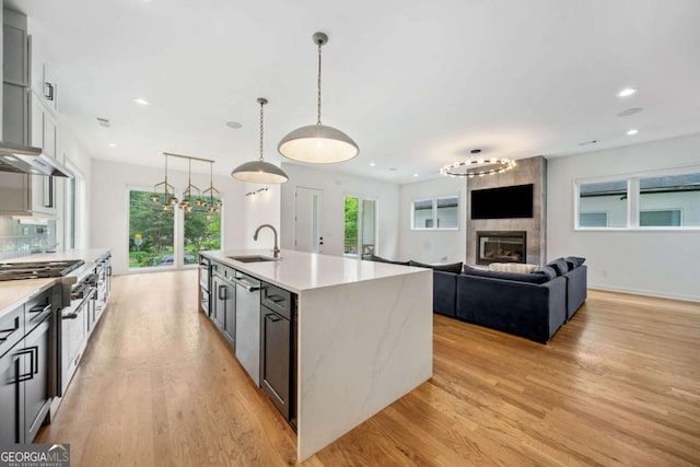 32 Walthall St NE Unit A, Atlanta, GA 30307 - kitchen with light wood-type flooring, light countertops, a large fireplace, an island with sink, and recessed lighting