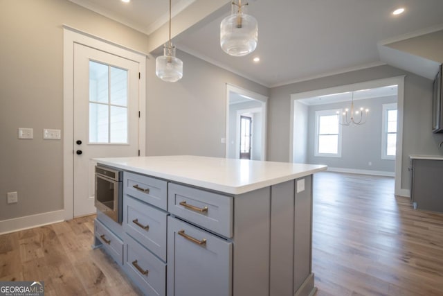 145 Holmes Ave, Athens, GA 30606 - kitchen with gray cabinets, crown molding, light wood finished floors, light countertops, and a kitchen island