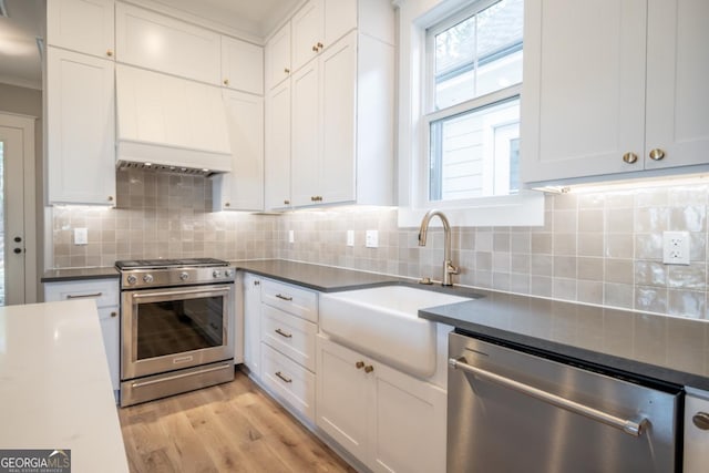 145 Holmes Ave, Athens, GA 30606 - kitchen featuring appliances with stainless steel finishes, light wood-type flooring, white cabinetry, decorative backsplash, and ornamental molding