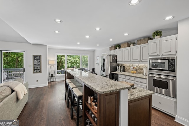3648 Sope Creek Farm SE, Marietta, GA 30067 - kitchen featuring stainless steel appliances, an island with sink, recessed lighting, light stone counters, and dark wood-type flooring